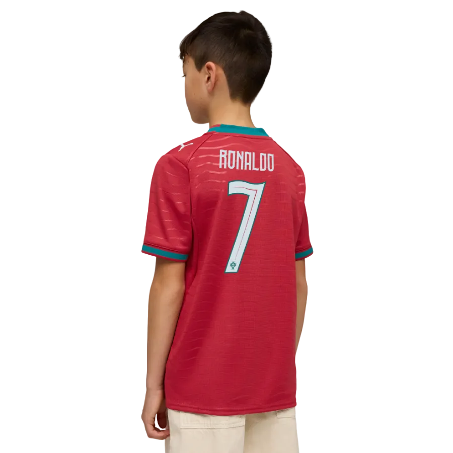 Back view of a boy wearing a red soccer jersey with "RONALDO 7" on the back and light-colored pants, set against a black background.